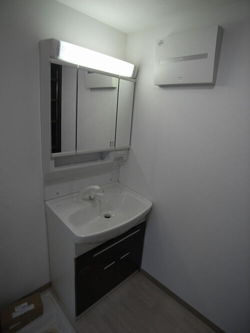 洗面台は白にブラウンが映えるデザイン。 鏡の裏に収納が隠れています。