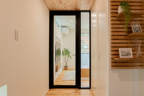 【玄関】天井、床は桜の無垢板張りです。そして奥に見えるアクリル板のドア。縁を黒にすることで空間がグッと締まります。