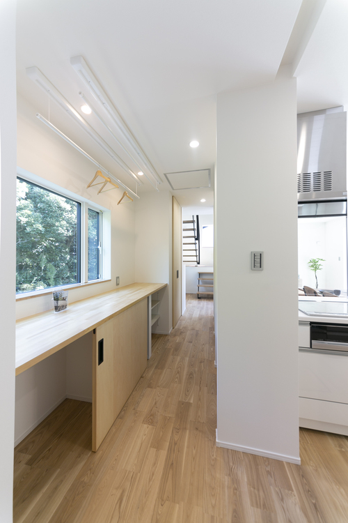 【家事スペース】大きな収納棚と洗濯物を畳んだり、アイロンかけをするためのスペースを廊下に設けました。幅を広くとり、そのままリビングへも抜けれるようになっています。